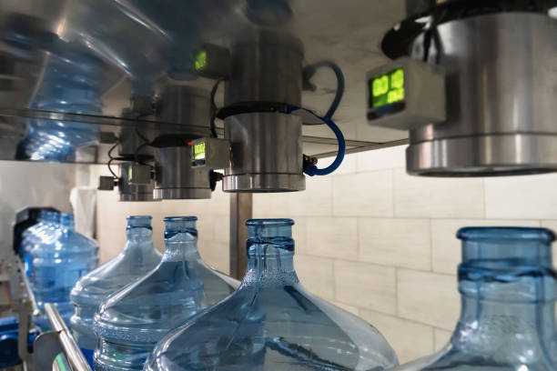 Automatic integrity check of plastic bottles or gallons under pressure at purified drinking water plant or factory, close up.