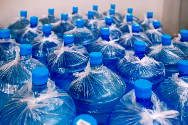 A row of large bottles of drinking water for a cooler. Water delivery. Packed and ready to be shipped to customers, blue bottles, finished goods warehouse, clean water